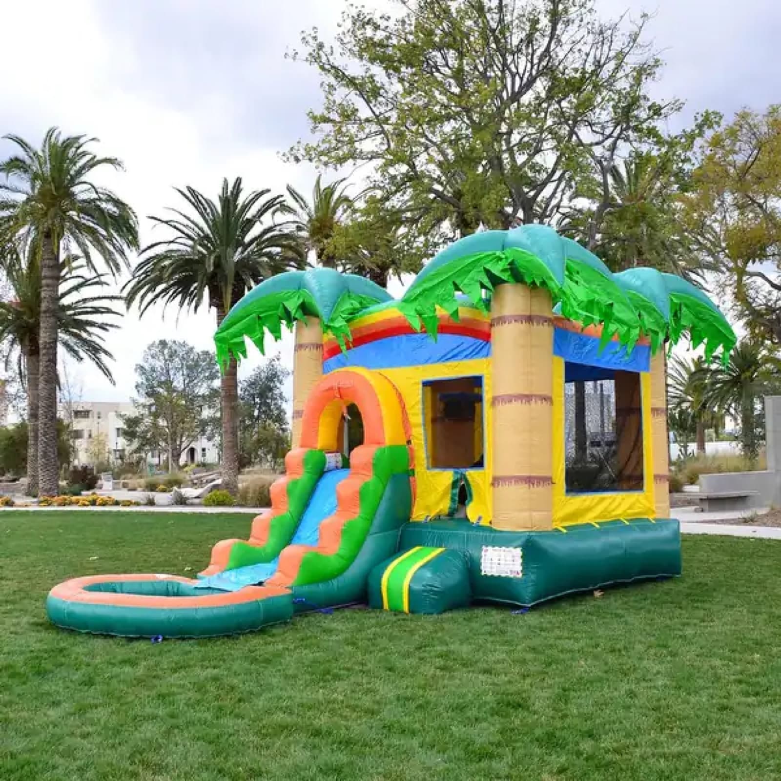 Tropical combo bounce house with palm trees, slide, and splash pool